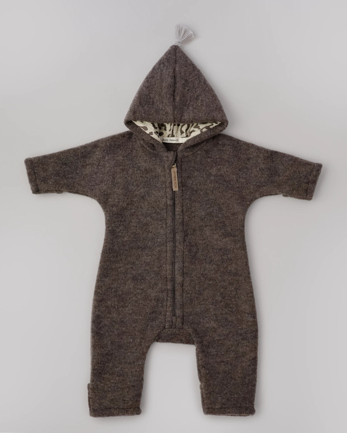 Kitz Heimat Wollfleece-Overall Chocolate/Leo in Vorderansicht mit spitzer Kapuze, Leopardenmuster im Kapuzenfutter, heller Quaste und Reißverschluss.