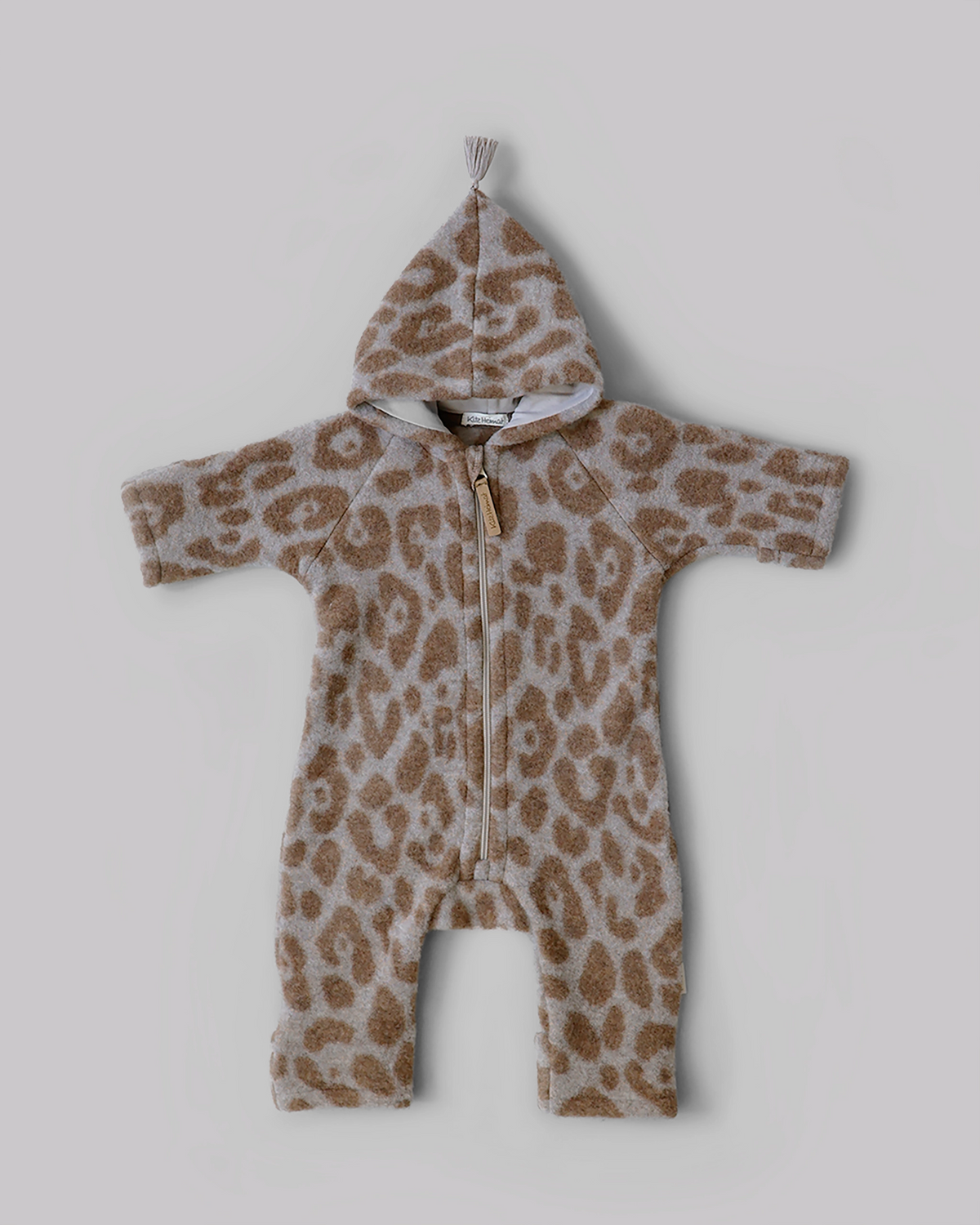 Kitz Heimat Wollfleece-Overall Leo Beige/Nude aus Bio-Merinowolle mit hellem Leopardenmuster, spitzer Kapuze mit Quaste und Reißverschluss in Vorderansicht.