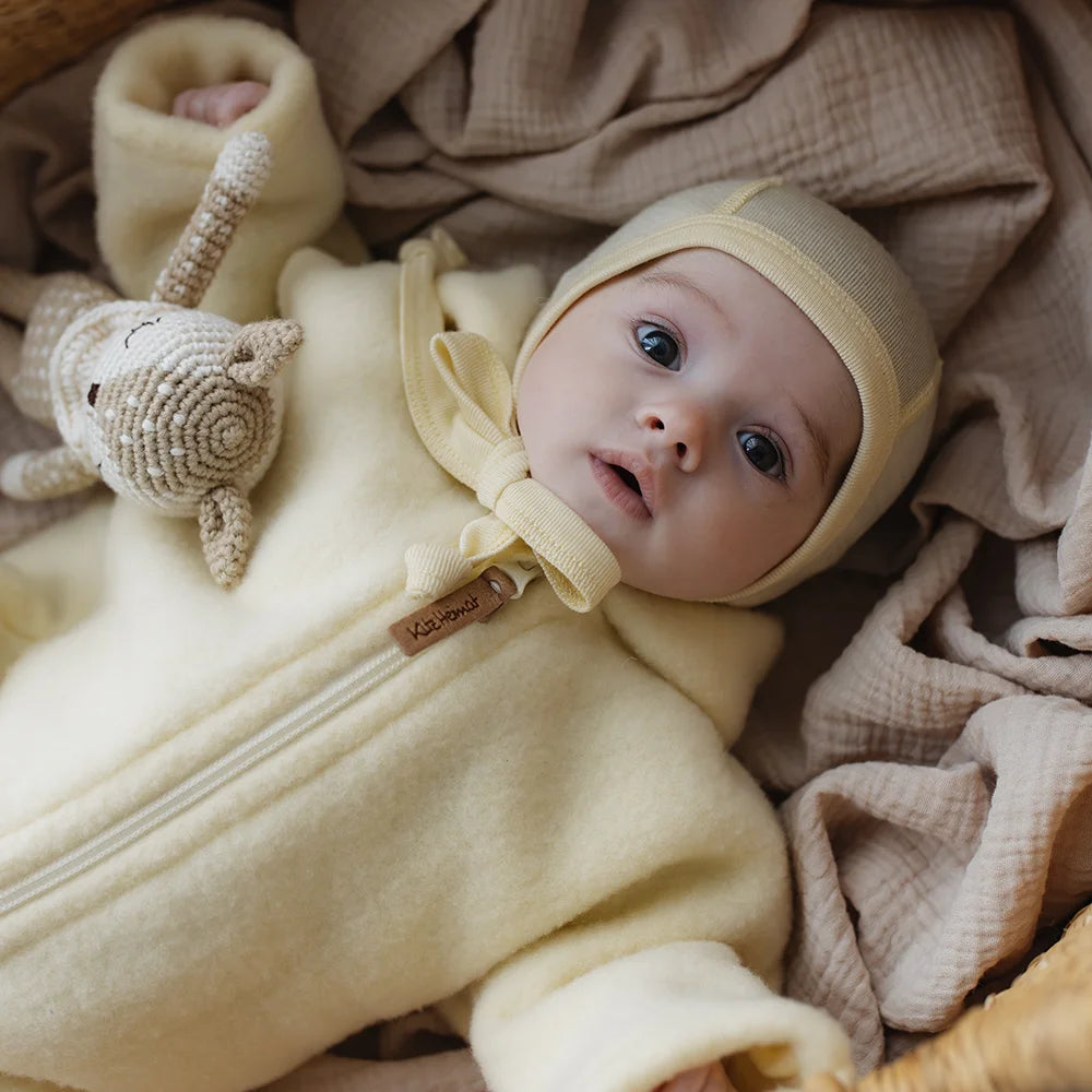 Overall mit Kapuze aus Bio-Merino-Wollfleece in Butter Yellow Milk, Tragebild mit Baby