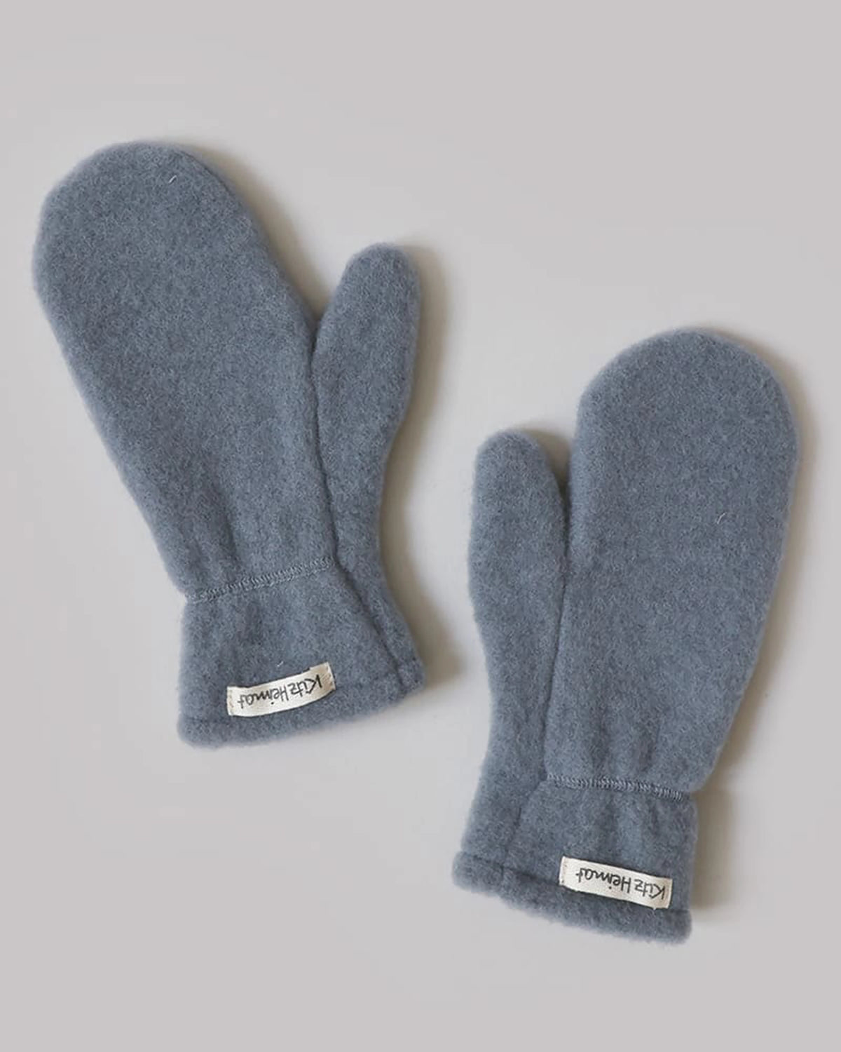 Kitz Heimat Wollfleece-Faustlinge Cloudy Blue ohne separaten Daumen aus Bio-Merinowolle mit elastischen Bündchen und Markenetiketten.