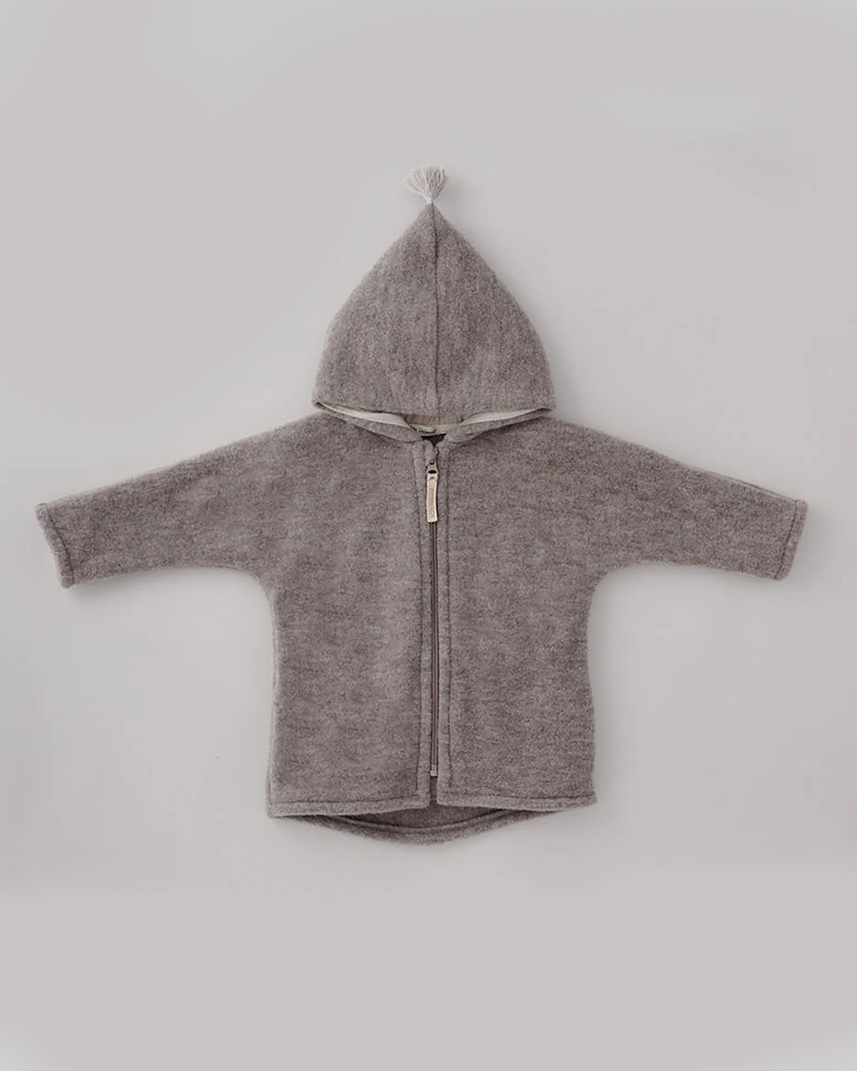 Kitz Heimat Wollfleece-Jacke Greige/Nude in Vorderansicht mit spitzer Kapuze, heller Quaste, durchgehendem Reißverschluss und leicht abgerundetem Saum.