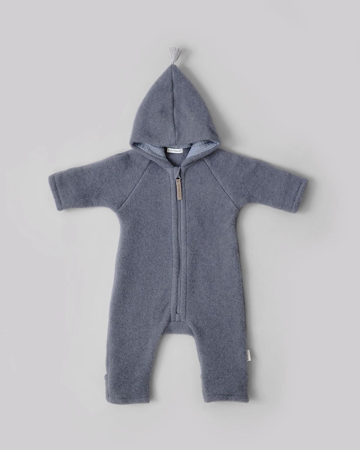 Kitz Heimat Wollfleece-Overall Cloudy Blue/Blue aus Bio-Merinowolle in Vorderansicht mit spitzer Kapuze, heller Quaste und durchgehendem Reißverschluss.