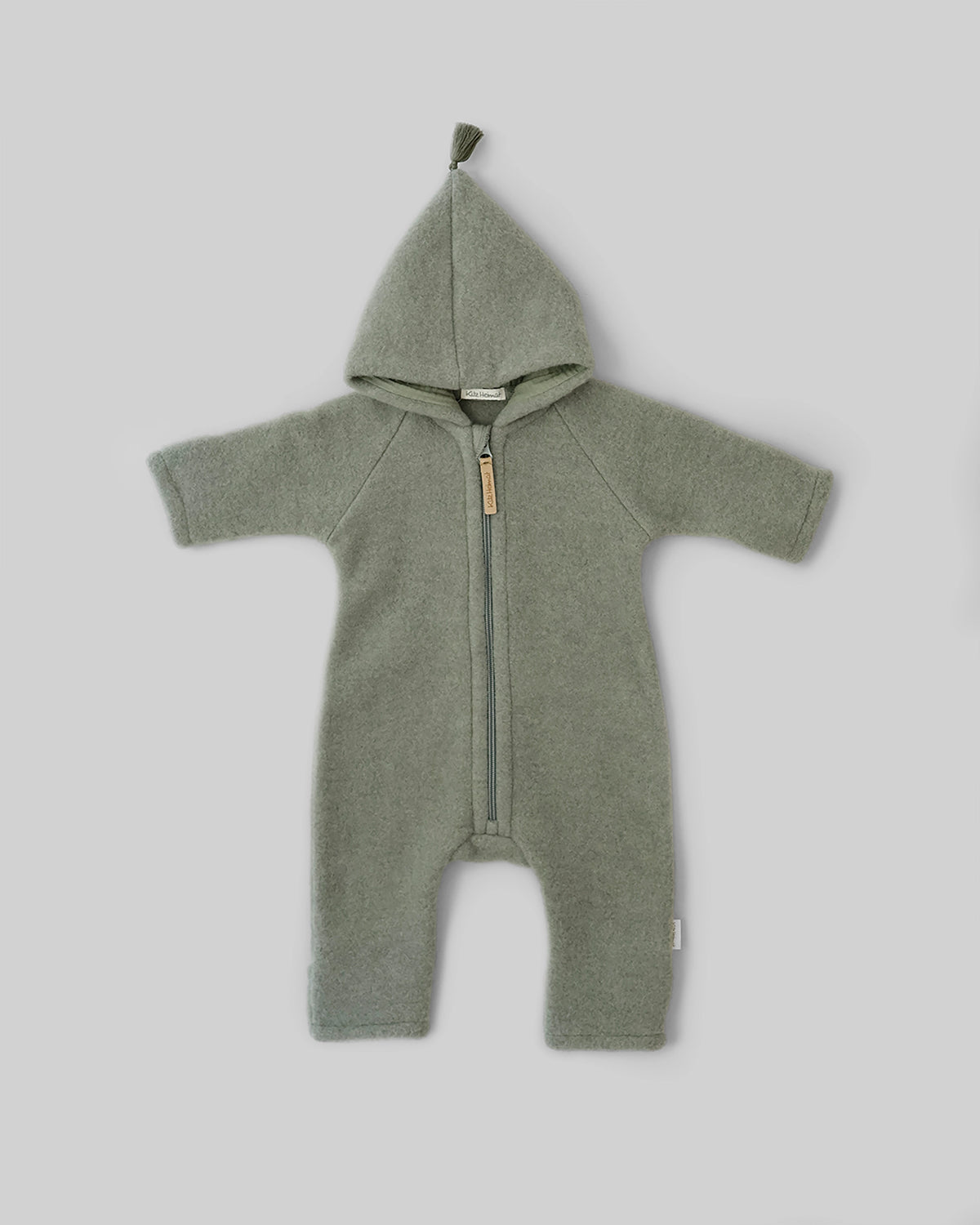 Kitz Heimat Wollfleece-Overall aus Bio-Merinowolle in Frost Green/Green mit spitzer Kapuze, Quaste und Reißverschluss in Vorderansicht.