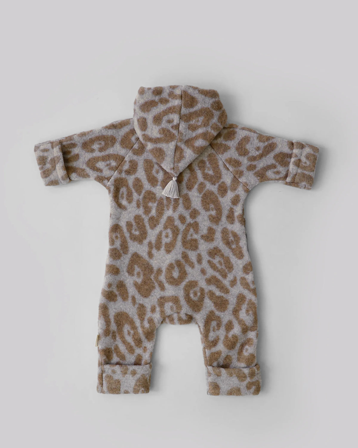 Kitz Heimat Wollfleece-Overall Leo Beige/Nude aus Bio-Merinowolle in Rückansicht mit hellem Leopardenmuster, Kapuze mit Quaste und umgeschlagenen Bündchen.