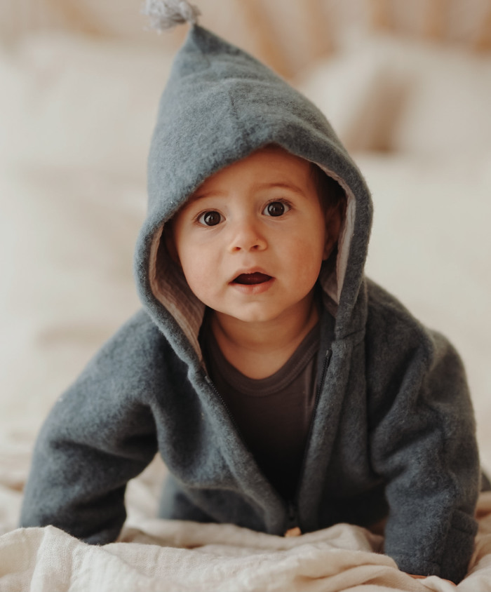 Ein Baby trägt einen Merino Overall in Frosty Blue.
